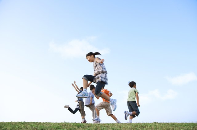 School children jumping at riverbank, copy space