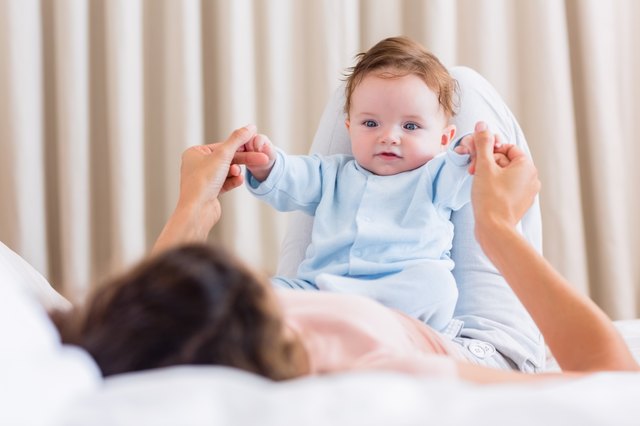 Baby playing with mother in bed