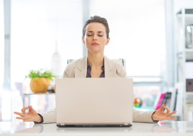 Business woman meditating near laptop