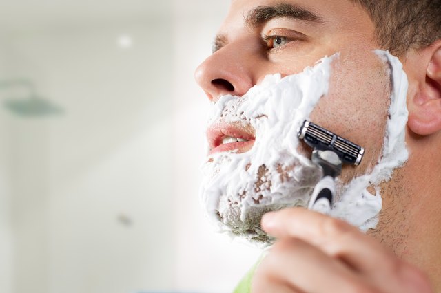 Happy middle aged man using razor to shave