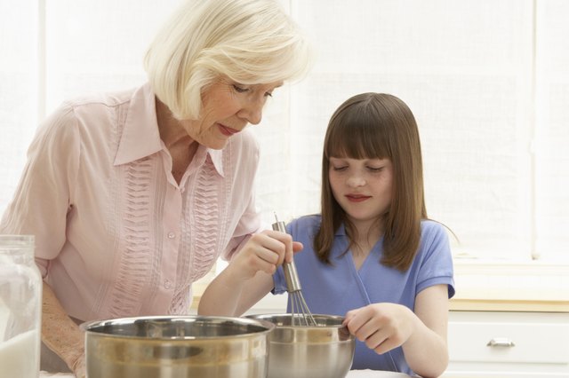 Granddaughter (8-10) and grandmother mixing ingredients in bowl