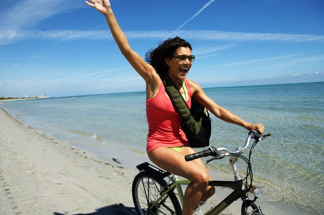 Young woman on bicycle waving, smiling, close-up