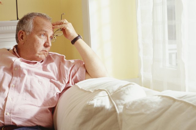 Thoughtful man sitting on sofa in living room, portrait