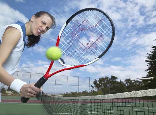 Woman holding tennis racket with hole in it and tennis ball in air