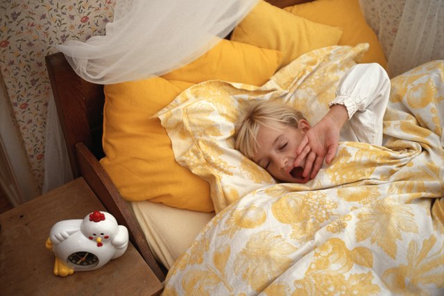 Girl (6-7) yawning in bed, eyes closed, elevated view