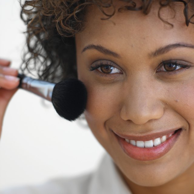 Close-up of young woman applying blusher with brush