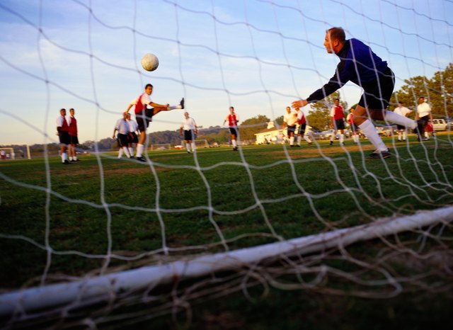 Soccer Player Kicking Ball into Goal
