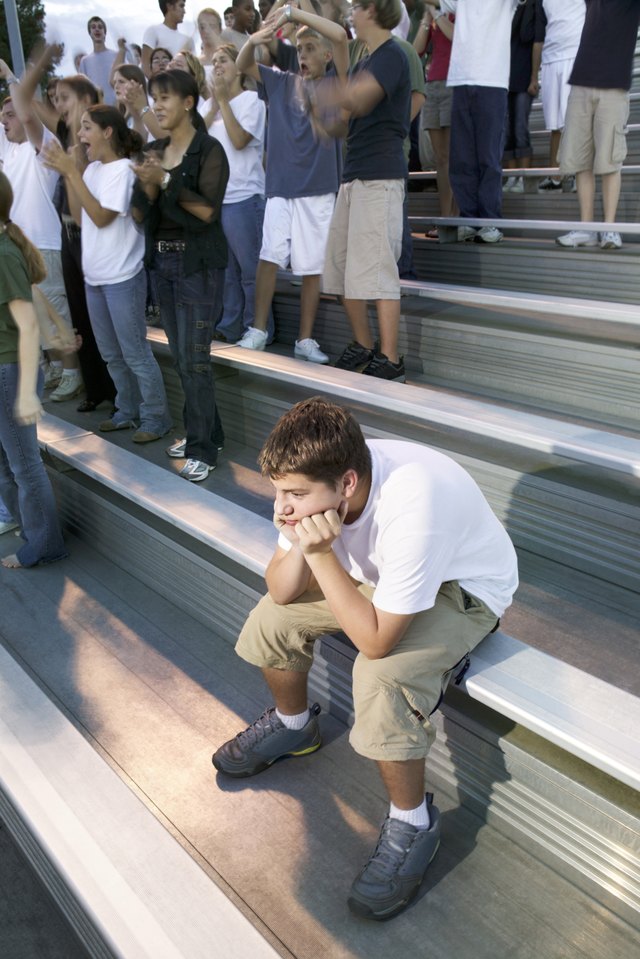 Teenage boy alone near crowd