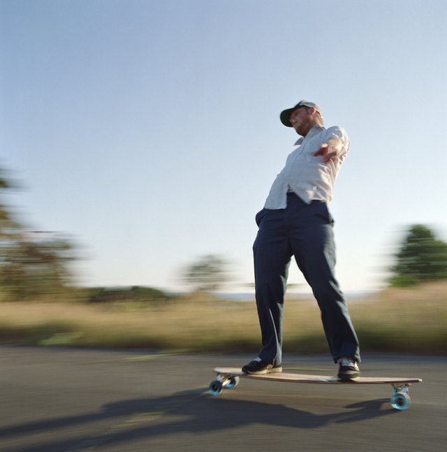 Young man skating on longboard, side view (blurred motion)