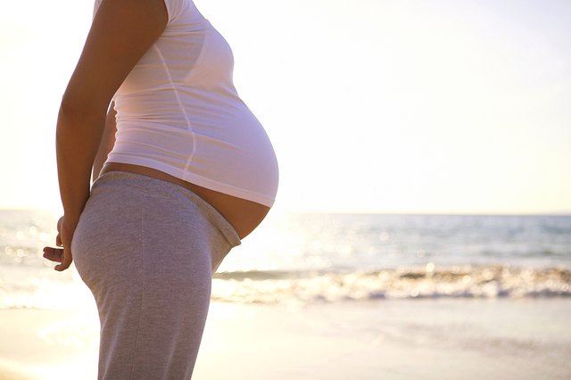 Torso of pregnant woman on beach