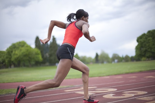 Young female sprinter accelerating, running, side view