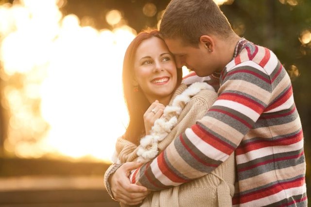 Happy young couple embracing while walking in a park on a sunny autumn day