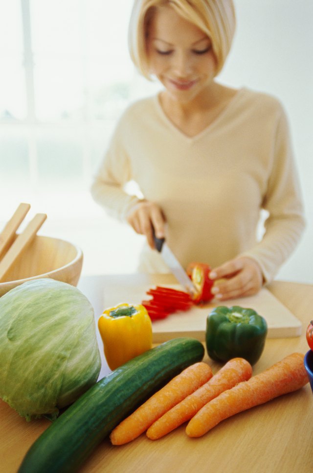 close-up of a woman cutting vegetables on a cutting board