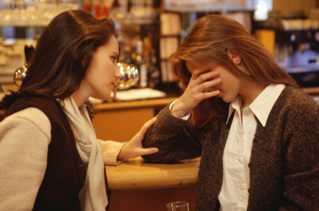 Young woman comforting friend at bar