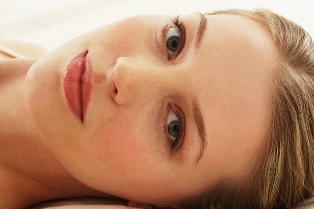 Young woman lying on bed, portrait, close-up