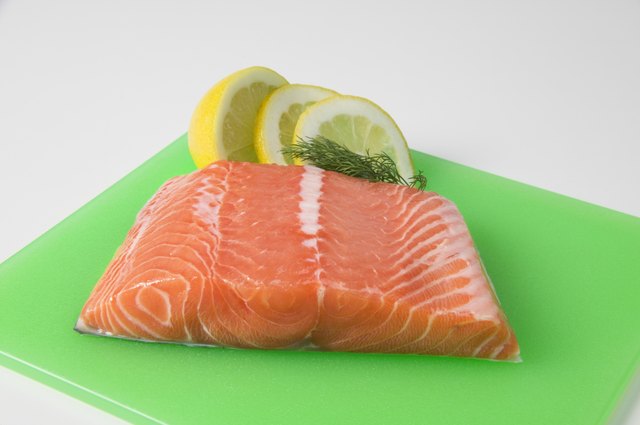 Salmon fillet on plastic cutting board with garnishes