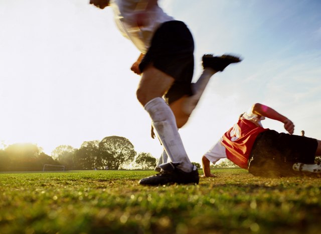 Soccer players running on pitch, low section (blurred motion)