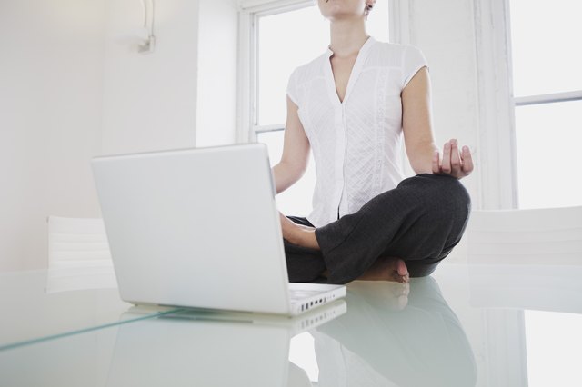 Mid-adult woman in lotus pose or yoga pose in office
