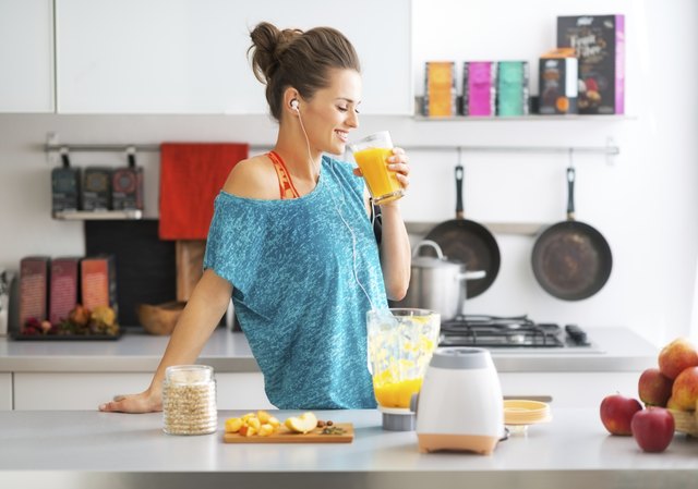 happy fitness young woman drinking pumpkin smoothie in kitchen