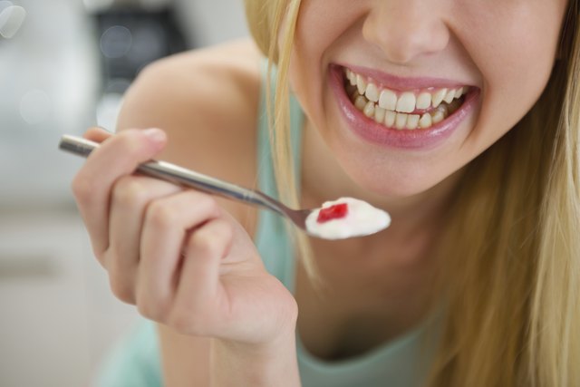 Closeup on spoon with yogurt in hand of smiling girl