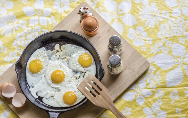 fried eggs in a cast iron pan on wood board.