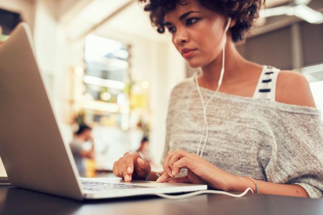 Portrait of young woman looking busy working on laptop at a cafe. African woman sitting in coffee shop using laptop.