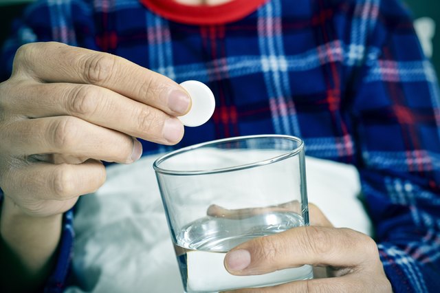 man putting an effervescent tablet into a glass with water