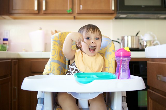 Little Girl Eating in High Chair