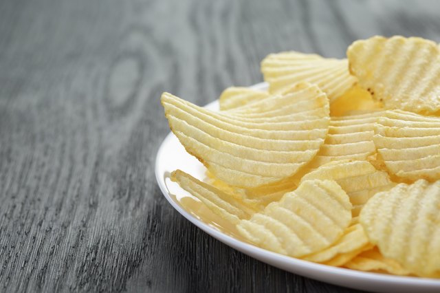 rippled potato chips in white plate on wood table
