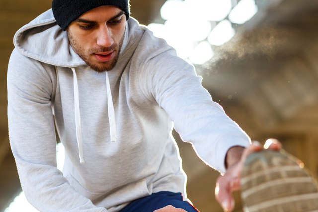 Young man stretching his muscles under the bridge.