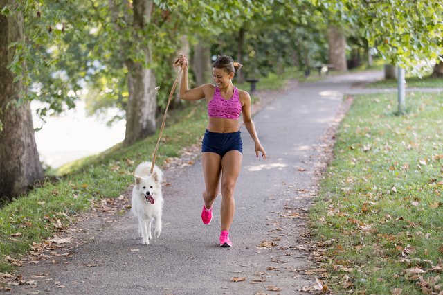 Young attractive sport girl running with dog in park