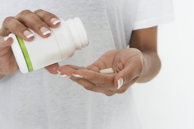 Woman holding bottle of pills, mid section