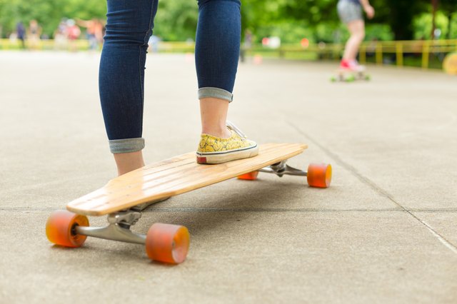 Teenage girl practicing riding long board.