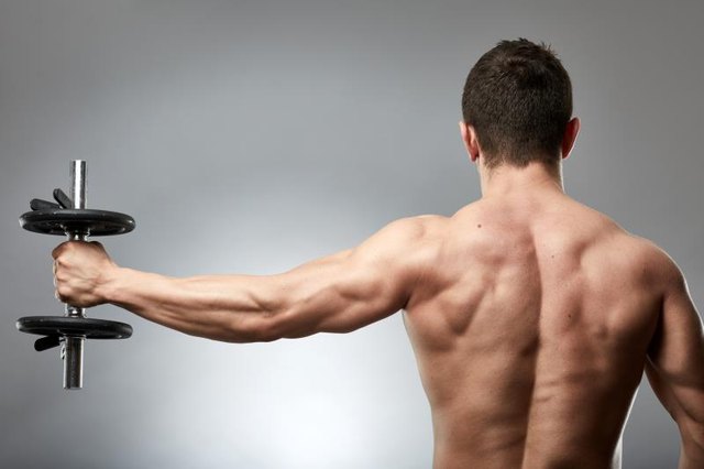 Man doing shoulder workout with dumbbell on gray background