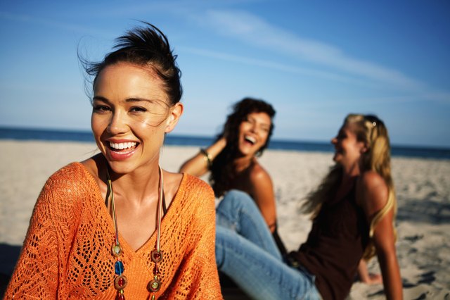 Young women smiling on beach, portrait, close-up (focus on foreground)