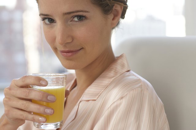 Young woman wearing pyjamas holding glass of juice, close-up, portrait