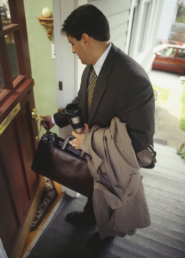 Businessman opening front door to house
