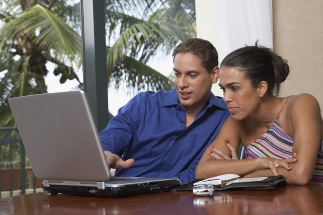 Mid adult man and a young woman sitting in front of a laptop