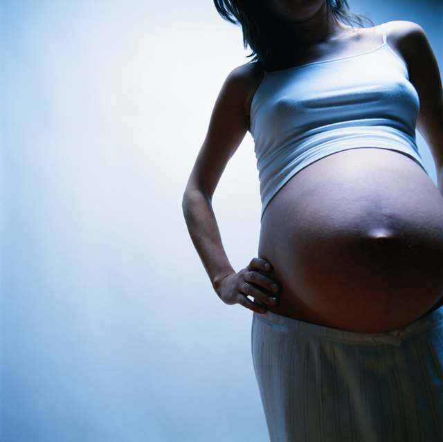 Pregnant woman with hand on hip, mid section