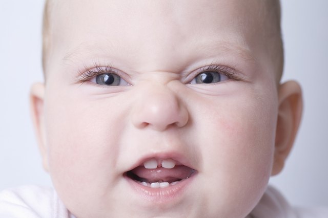 Baby boy pulls funny face with scrunched up nose