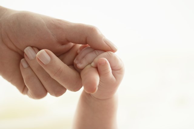 Baby girl (3-6 months) holding woman's finger, close-up