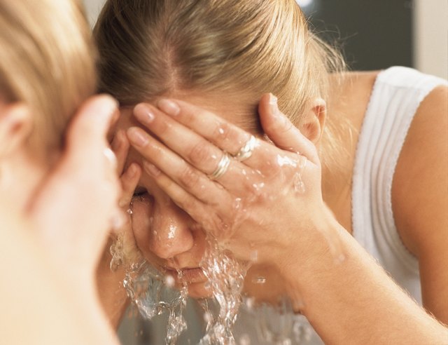 beautiful woman splashing face with water with reflection