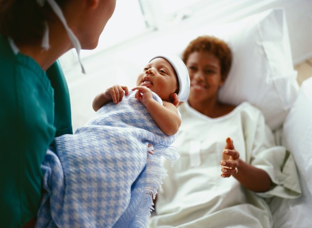 elevated close-up view of a doctor handing a new born baby to the mother