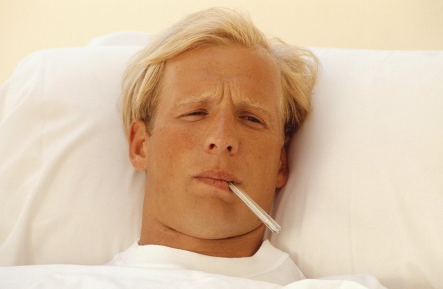 Man in bed with thermometer in mouth