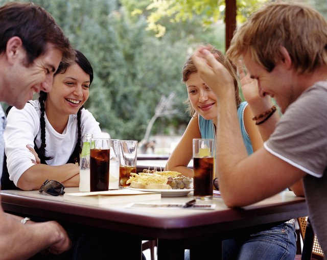 Two couples relaxing at outdoor cafe, smiling