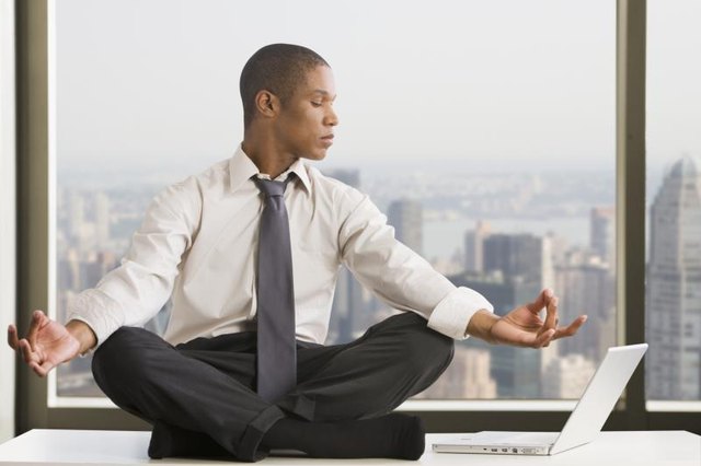 Mixed race businessman practicing yoga at desk