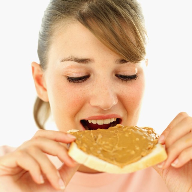 Close-up of a young woman eating a slice of bread with peanut butter