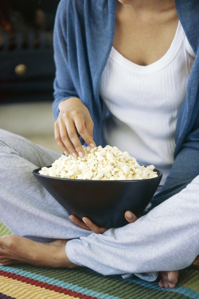 Mid section view of a young woman holding popcorns in a bowl