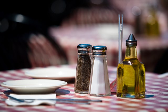 Salt and pepper shakers and olive oil on restaurant table