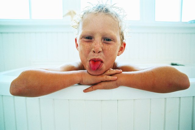 portrait of a young girl (6-8) in a tub sticking out her tongue